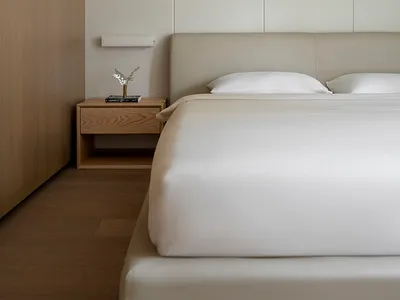 A modern minimalist bedroom with neutral tones and wood accents.