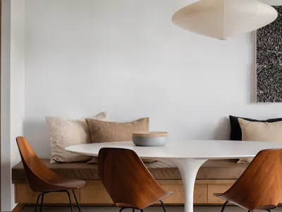 A modern kitchen and dining space featuring marbled countertops and wooden chairs.