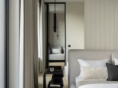 Modern minimalist bedroom featuring a light-colored upholstered bed with white and cream-colored pillows and a black circular