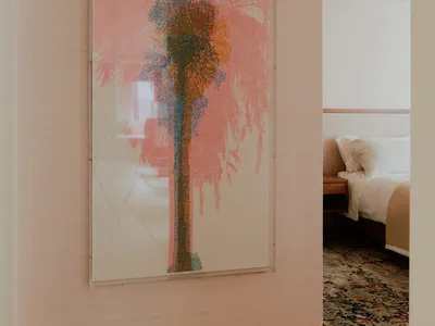 Minimalist bedroom featuring wooden furniture and a large framed artwork depicting a palm tree.