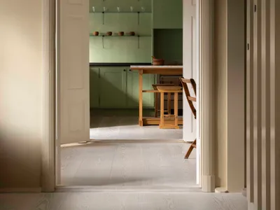 A minimalist residential kitchen with wooden elements and a light wood floor.