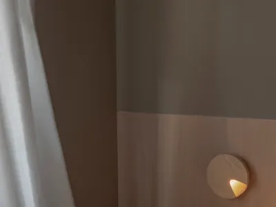 Minimalist bedroom with wooden walls, light fixture, and sheer curtains.