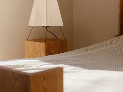 A minimalist bedroom featuring a wooden base lamp with a simple white fabric shade, creating a cozy and contemporary atmosphe