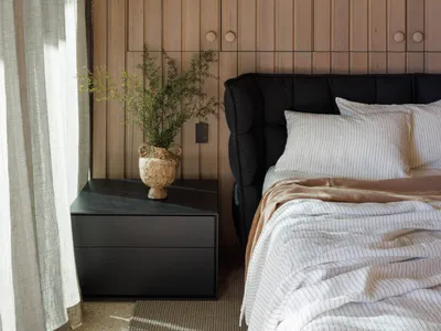 Minimalist bedroom featuring wooden walls, black furniture, and white bedding.