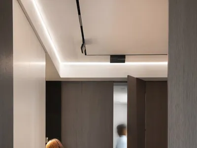 A minimalist bedroom featuring wood cabinets, metal accents, and a red carpet.