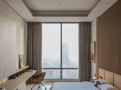 A minimalist bedroom with a grey bed and curtains, large window, and modern furniture.