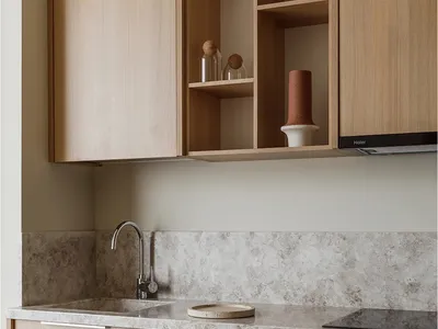 A modern kitchen featuring wooden cabinets, a sink, and a backsplash with a speckled pattern.