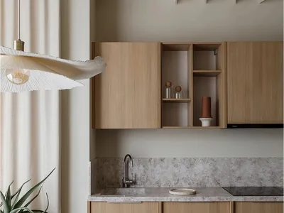 A modern kitchen with wooden countertops and cabinets, featuring a round table, bowls, and potted plant.