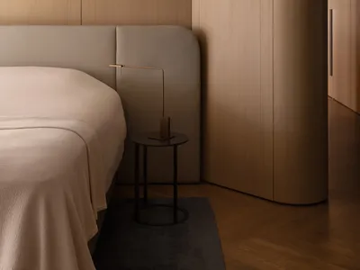 A minimalist bedroom with wooden walls and furniture, featuring a bed with a curved headboard and a small round side table wi