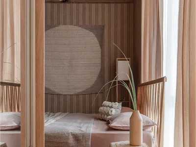 A modern minimalist bedroom with a wooden bed, a geometric patterned side table, and a round rug on the floor.