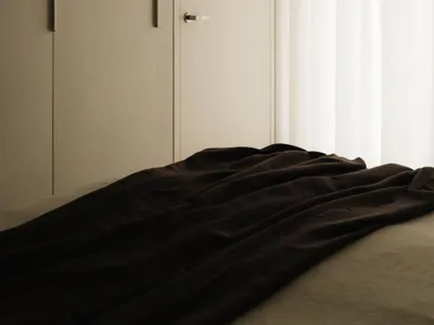 A minimalist bedroom with a fabric bedspread and wooden elements.