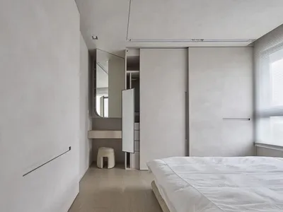 Contemporary minimalist bedroom featuring neutral-toned furniture and minimalist design elements.