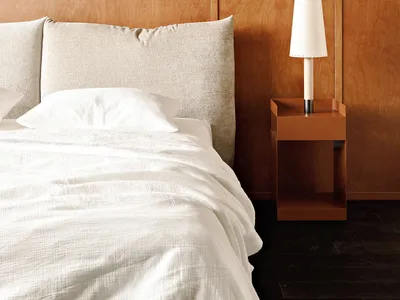 A minimalist bedroom with wooden panels and a white bed.