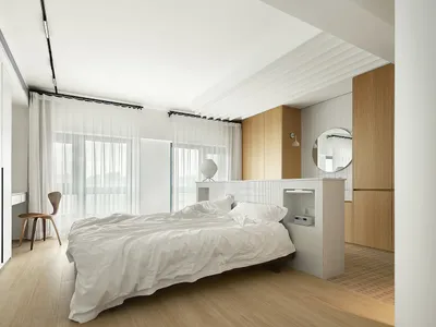 Modern minimalist bedroom featuring a platform bed with white tiled walls and wooden accents, surrounded by sheer curtains an