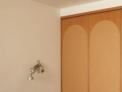 A minimalist bedroom with a wooden headboard and beige bedding and pillows.