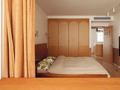 A modern minimalist bedroom with wooden furniture and a single bed