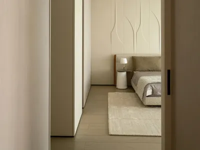 A neutral-colored minimalist bedroom with a textured fabric upholstered bed and white accent table.