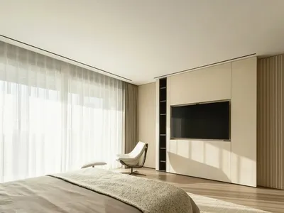 A minimalist bedroom with a large window, white bedding, and a white chair next to a large wooden cabinet.