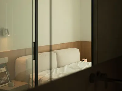 A minimalist bedroom with a fabric bed and wooden accents.