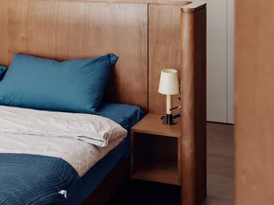 Minimalist bedroom with a wooden headboard and blue bedding.