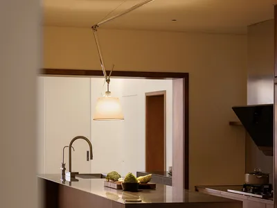 A modern, minimalist kitchen with a wooden countertop, featuring a variety of fruits on a cutting board.