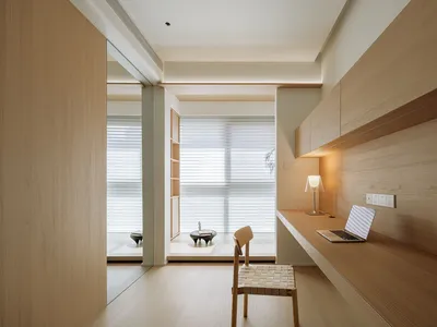 A minimalist home office with wooden furniture and a large window.