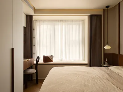 A modern bedroom featuring a beige bed with a cozy, comfortable fabric texture, accompanied by minimalistic window treatments