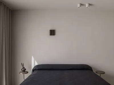 Modern minimalist bedroom with grey fabric bedspread and side tables.