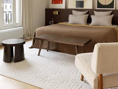 Minimalist bedroom with a brown bed, artwork, and mixed materials in a modern design.