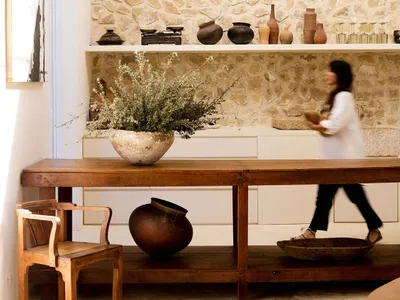 A minimalist residential kitchen featuring a wooden counter and stone wall with various decorative items.
