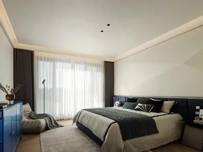 A modern bedroom featuring a large window with sheer curtains, a comfortable bed with a blue leather headboard, and a blue ca