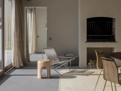 Industrial-style living room with concrete walls and minimalistic furniture, featuring a modern fireplace and large windows.