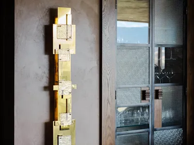 A modern living room featuring metallic wall art, glass flats, and texturized glass doors.