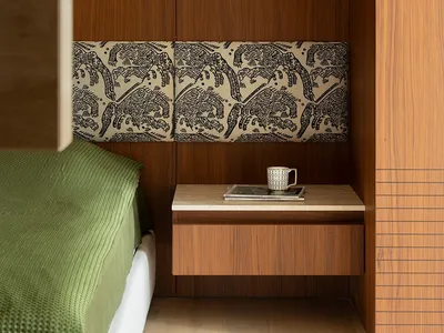 A minimalist bedroom features a floating wooden nightstand with a lamp and a cup and magazine on top.