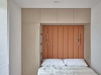 A minimalist bedroom with neutral-toned furniture and layered bedding.
