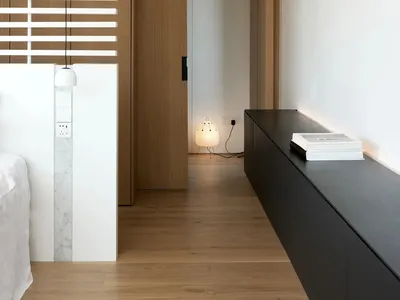 A modern minimalist bedroom featuring wooden elements and a sleek black sideboard.
