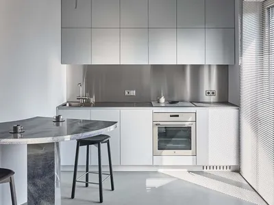 A modern minimalist kitchen with concrete countertops and white cabinetry.