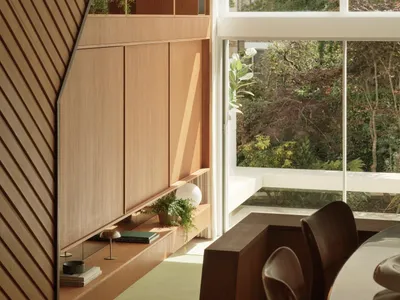 A modern kitchen with wooden shelves, green plants, and a glass window overlooking a garden.