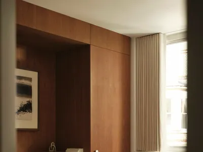 A modern minimalist bedroom featuring a wooden paneled wall, white bedding with gray stripes, and a window with beige curtain