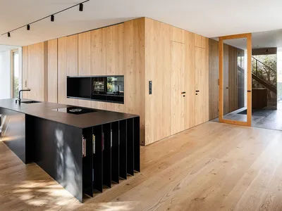 A modern minimalist kitchen with wooden cabinets and a black island.