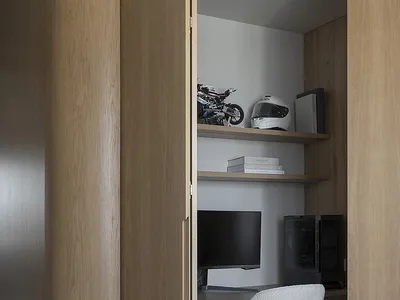 A modern home office with a wooden desk, shelves, and a white chair.