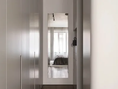 A minimalist bedroom featuring white walls, a white bed, and a wooden floor.
