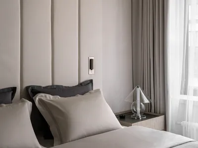 Minimalist bedroom with a bed, pillows, and a glass table lamp.