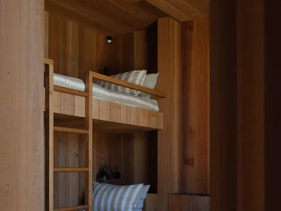 A minimalist bedroom featuring wood twin bunk beds with striped bedding.