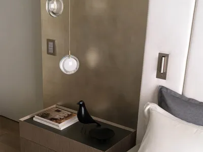 A modern minimalist bedroom featuring wooden furniture, a black bird figurine, and a metallic headboard.