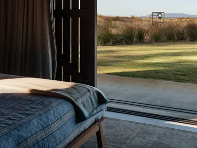 Bedroom with minimalist design featuring wood and concrete materials.