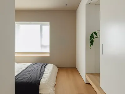 A minimalist bedroom featuring a wooden floor, metallic headboard, and fabric bedding.