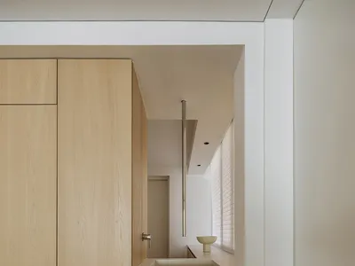 Modern minimalist kitchen with white laminate countertops, wooden cabinets, and a metal pipe structure