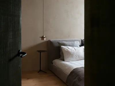 一間現代簡約臥室，配有低矮布面床頭板、白色的床具，以及木質地板。