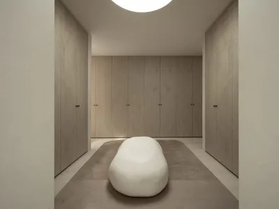 A minimalist bedroom with neutral tones and a sculptural white bench.